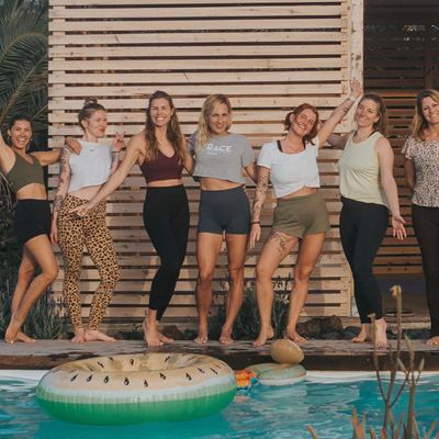Groep vrouwen lachend naast het zwembad tijdens een retreat